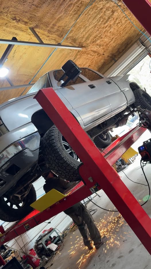 Exhaust work underway underneath a pickup truck on a shop lift, from the business Facebook group